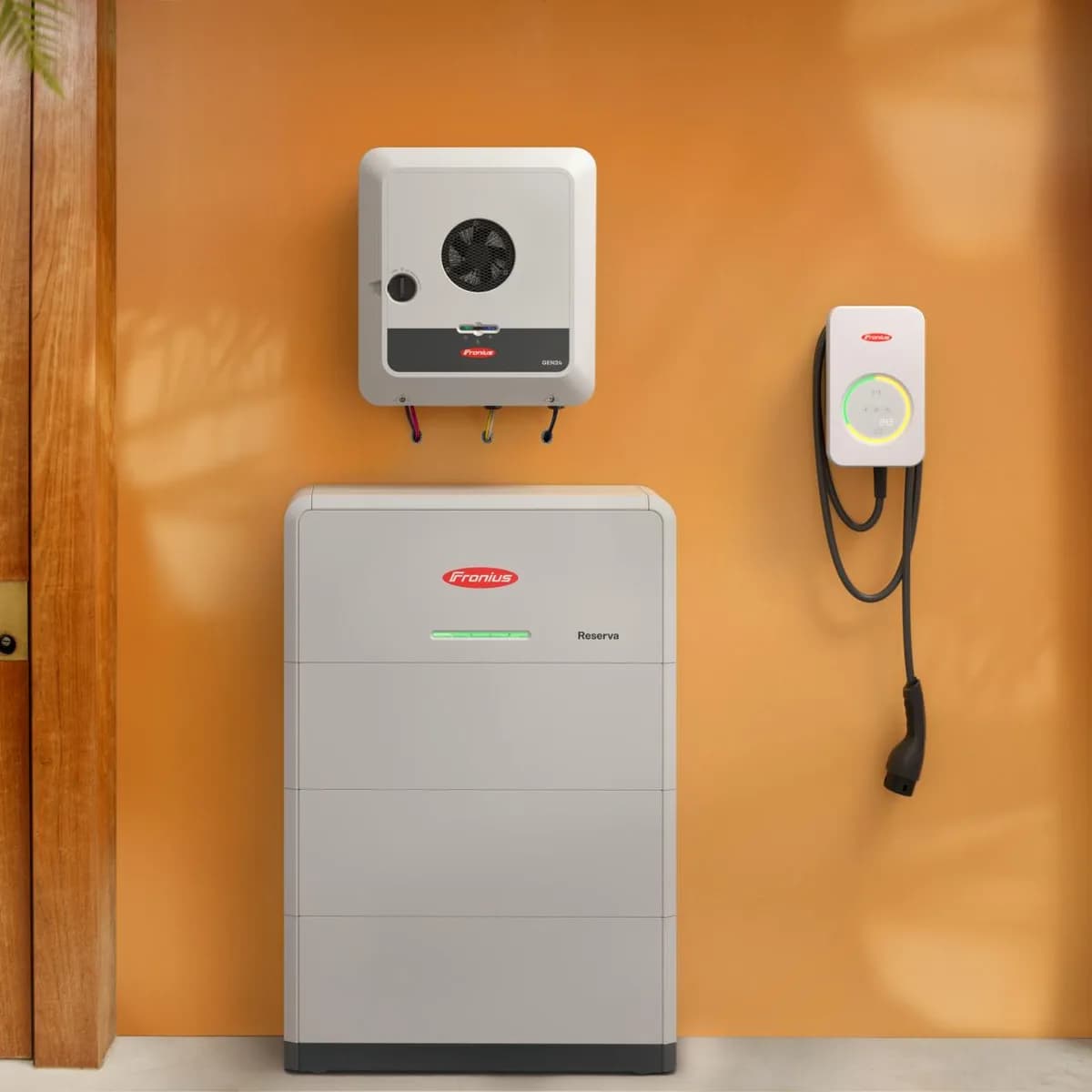 Fronius inverter, Fronius Reserva batteri og ladeboks på en orange væg ved en trædør