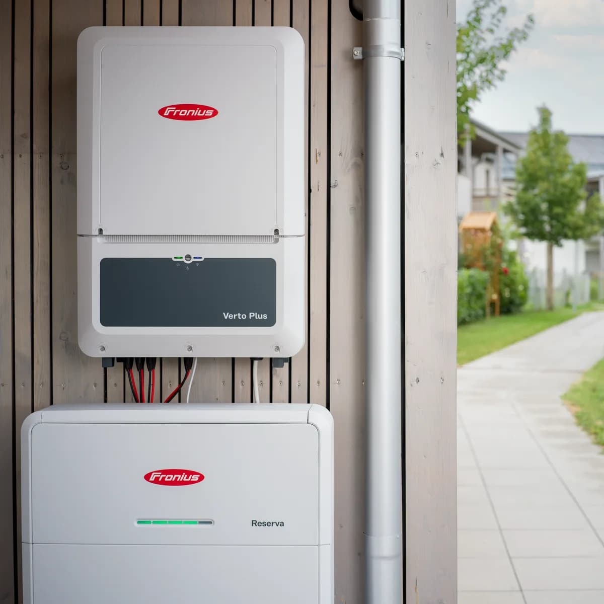 Fronius Verto Plus inverter og Reserva batteri på en træfacade ved en havegang