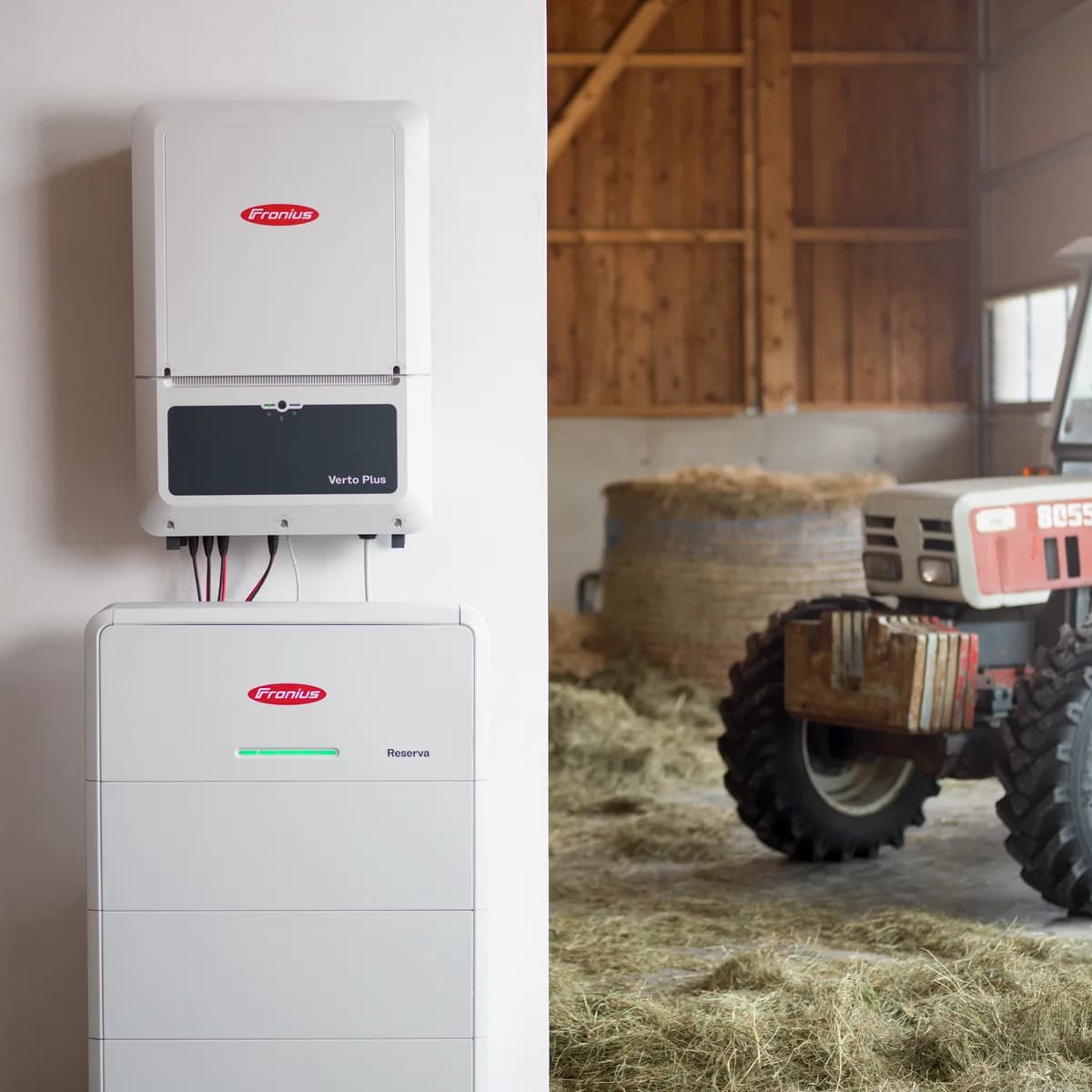 Fronius inverter og Reserva batteri på en lade, med en traktor og halmballer bagved